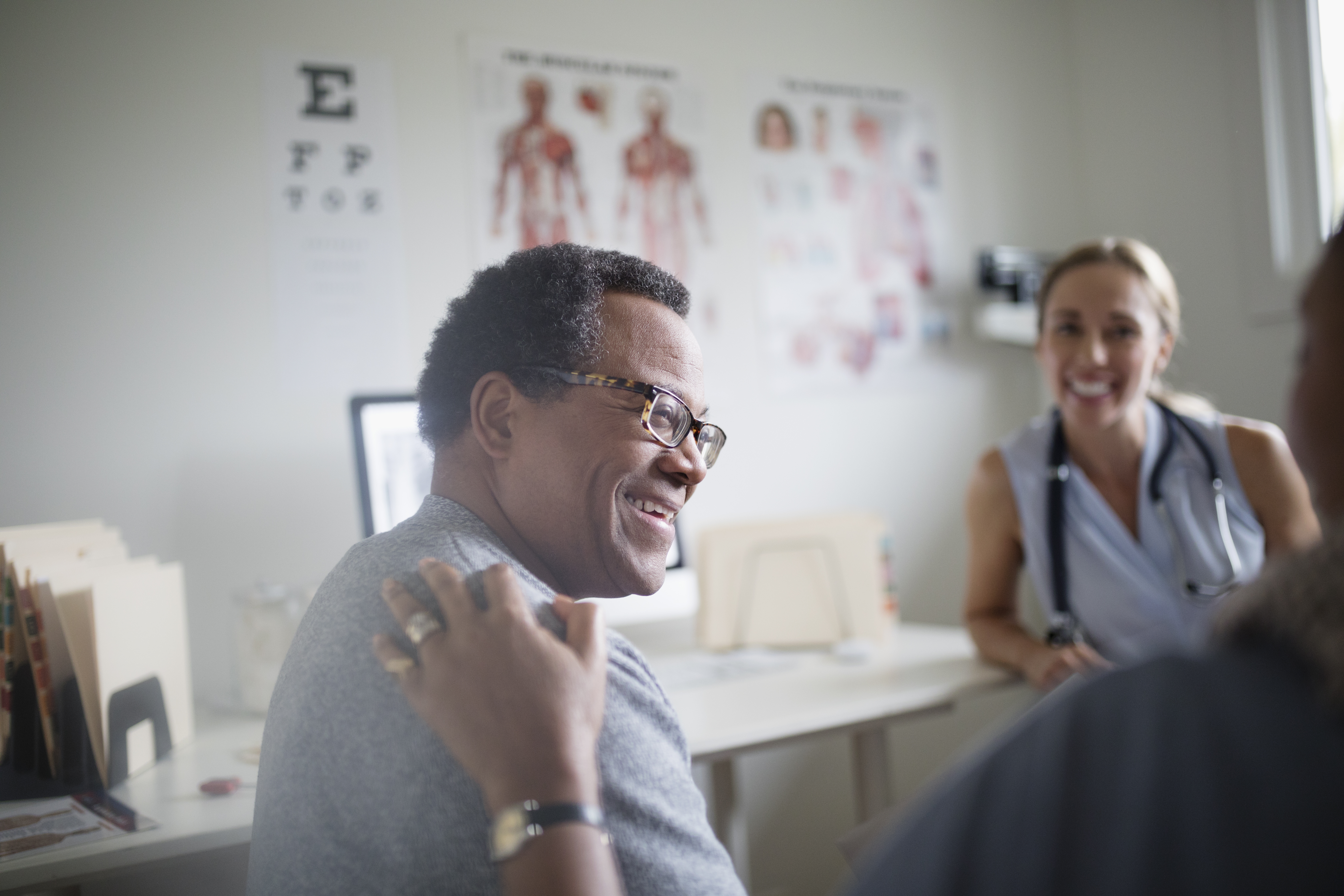 Smiling man talking with wife and doctor in examination room