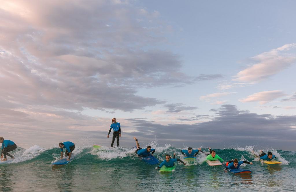 A group of surfers in the ocean at dusk