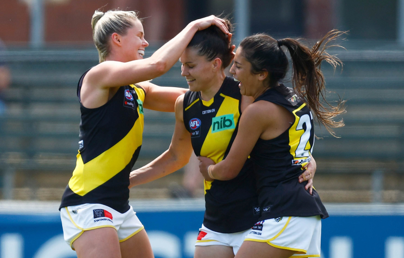 Three AFLW Richmond tigers women hugging each other in celebration