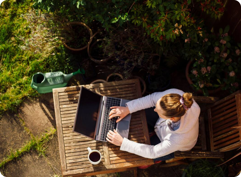Aerial shot of a woman outside on an outdoor table using her laptop