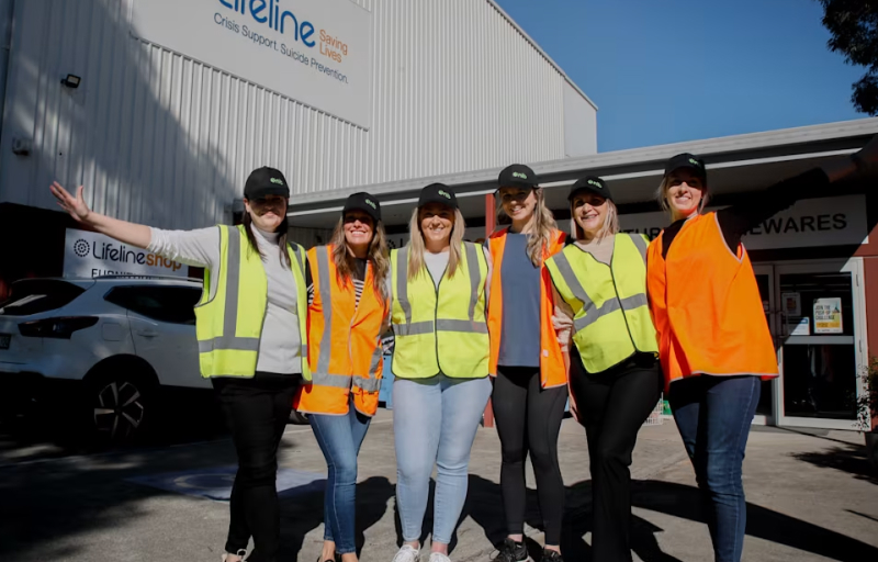 Six female nib employees volunteering at lifeline wearing hi vis vests and caps