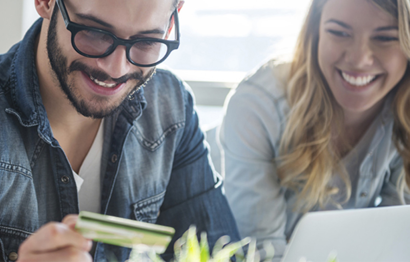 Man looking at his credit card smiling with his wife next to him