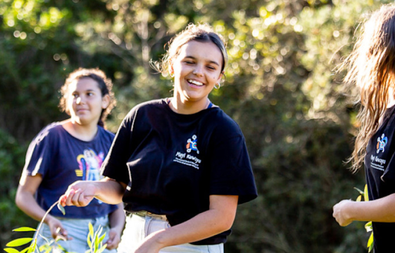 Smiling young female teen during cultural ceremony holding leaves