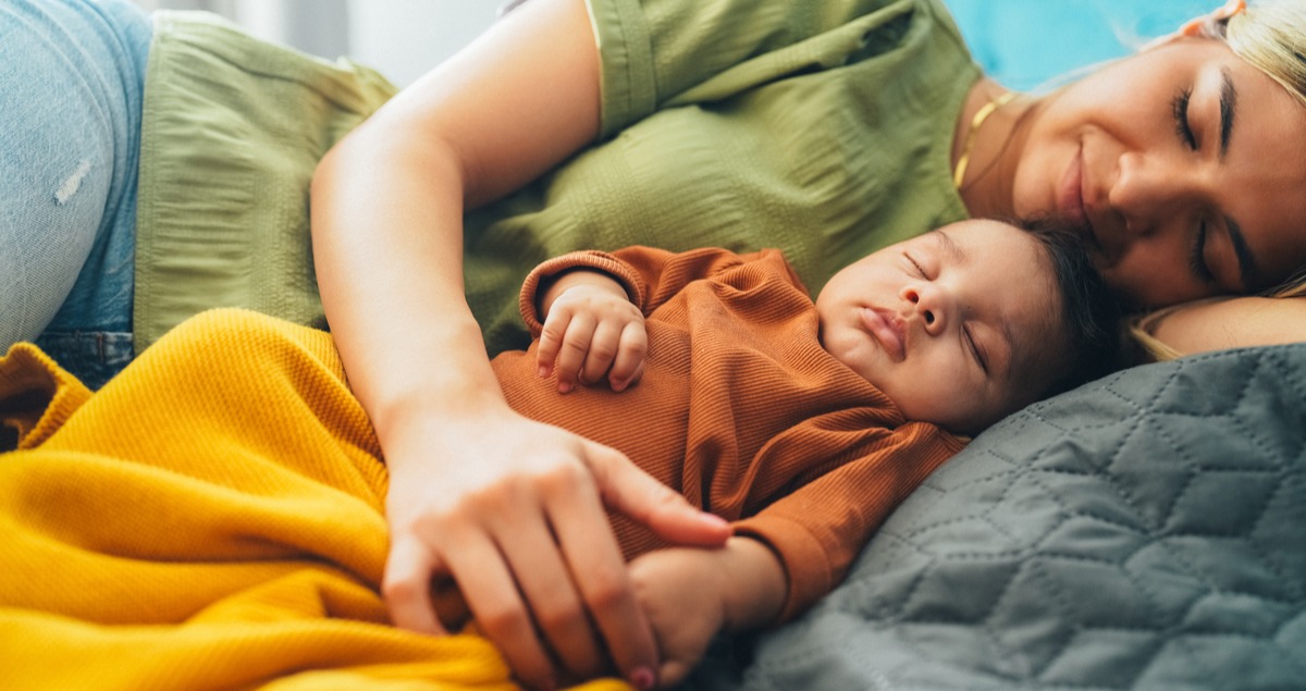 Young mother and baby napping at home.