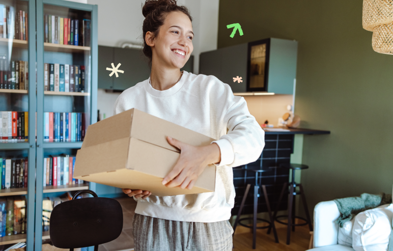 Woman smiling while holding cardboard packages.