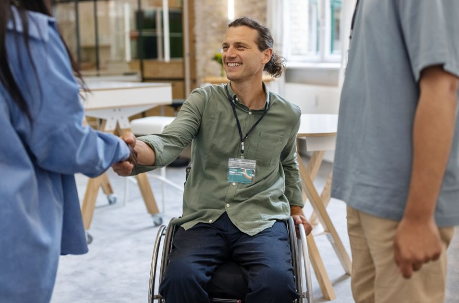 A man in a wheelchair shaking hands with another person.