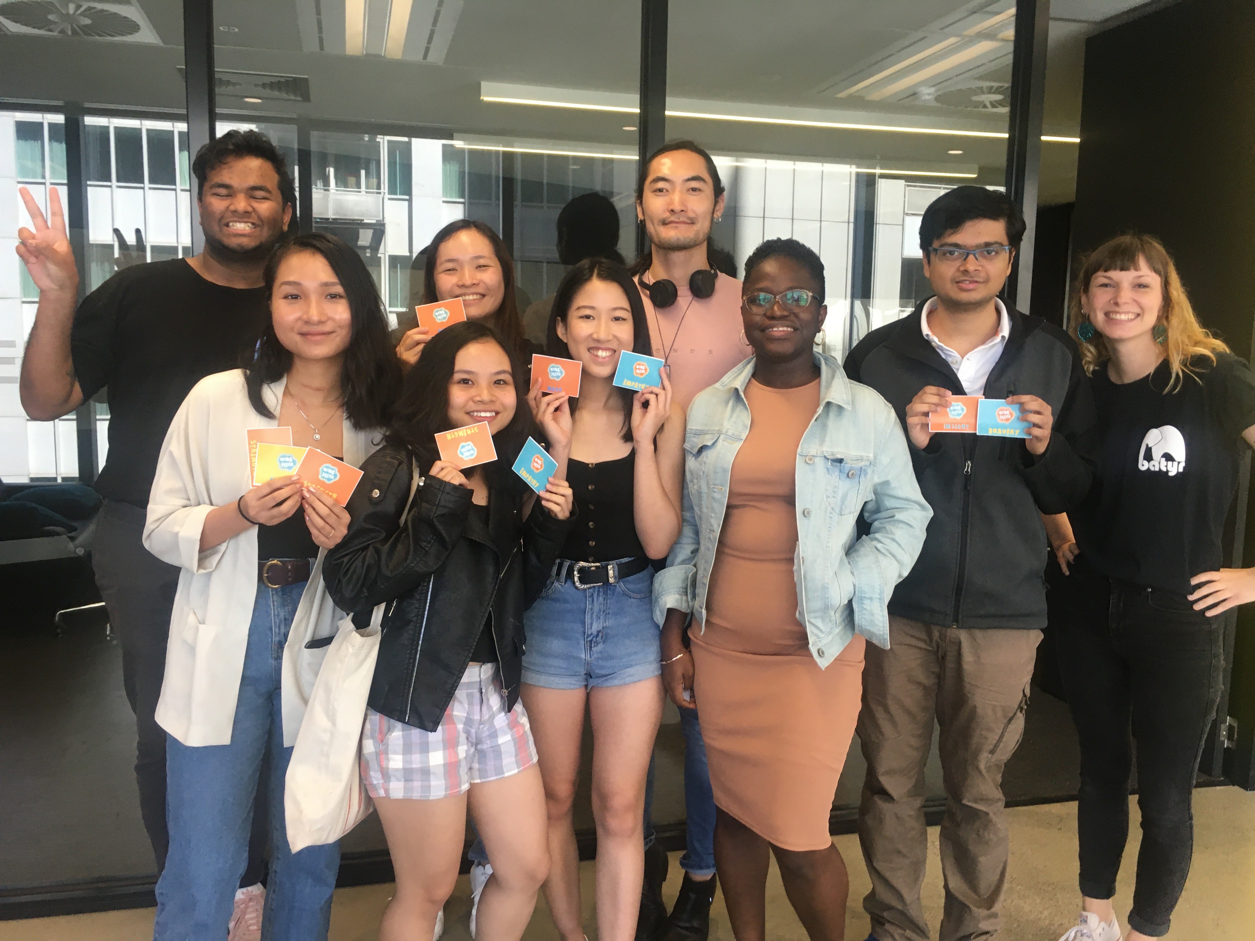 A group of batyr international students, mixed race. Smiling and holding up cards