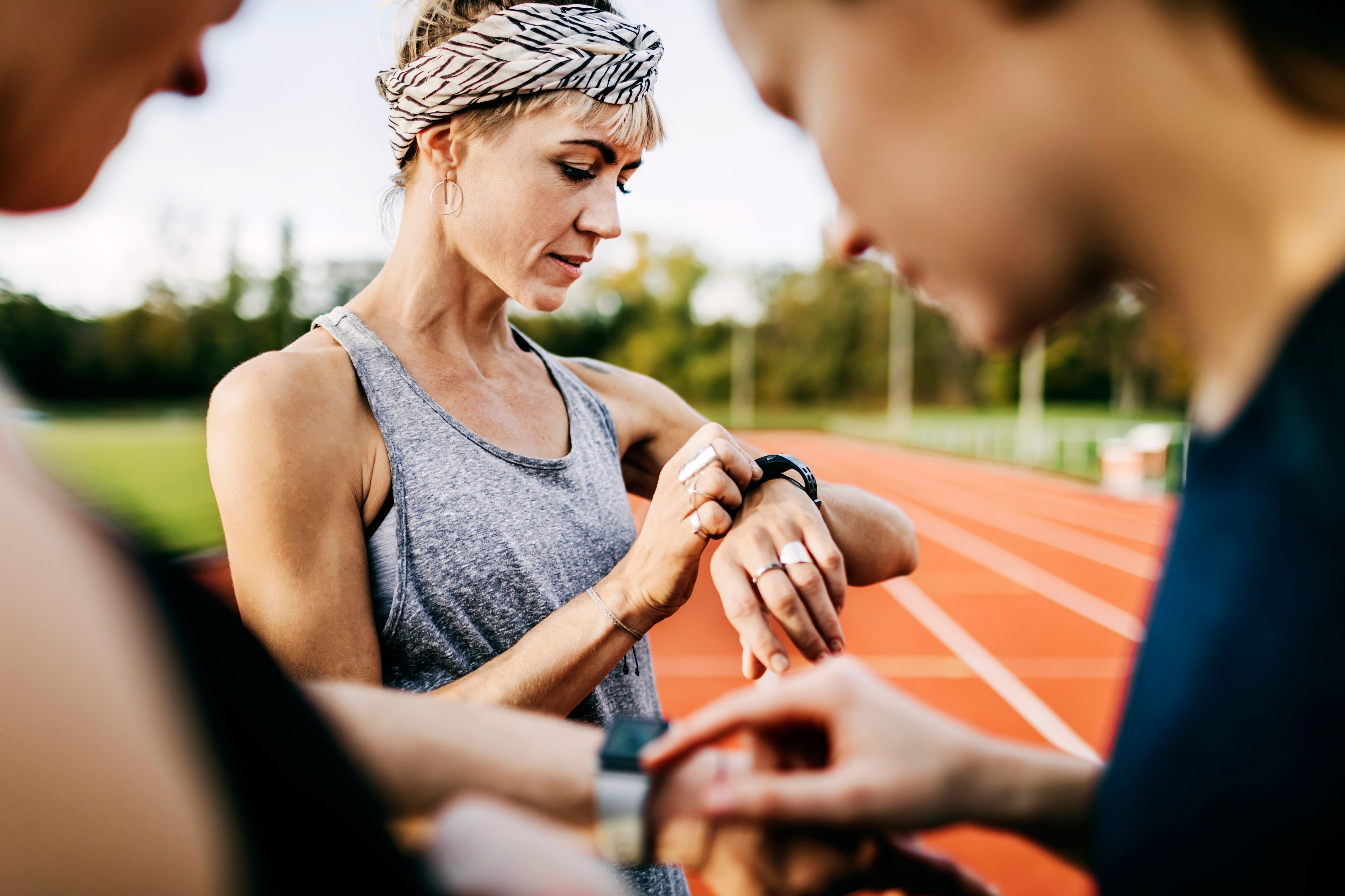 A woman on a running track checks her fitness watch