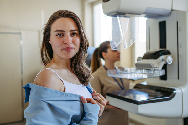 A woman in a doctor's office in front of a mammogram machine