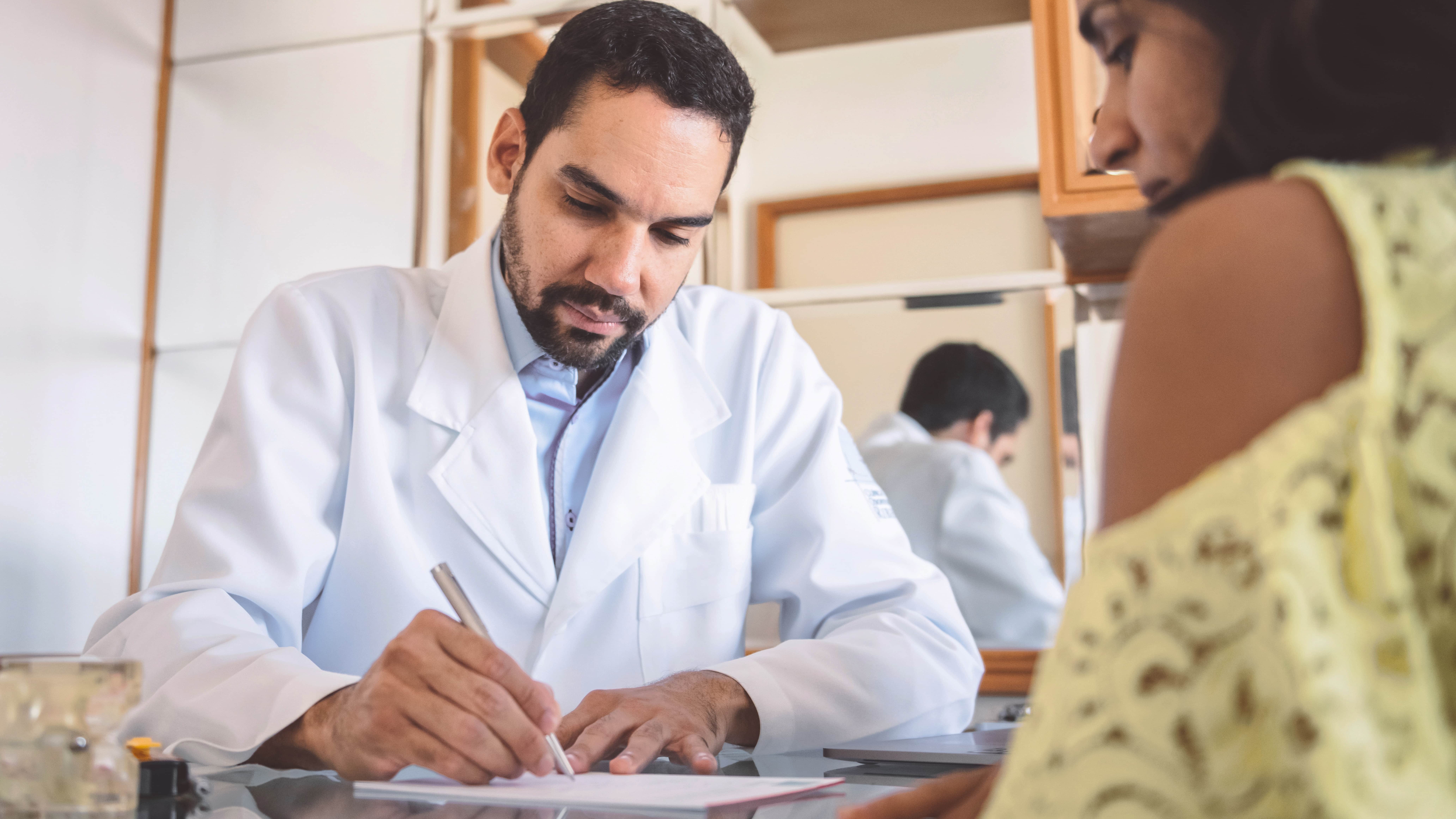 Doctor writing a referral for his patient.