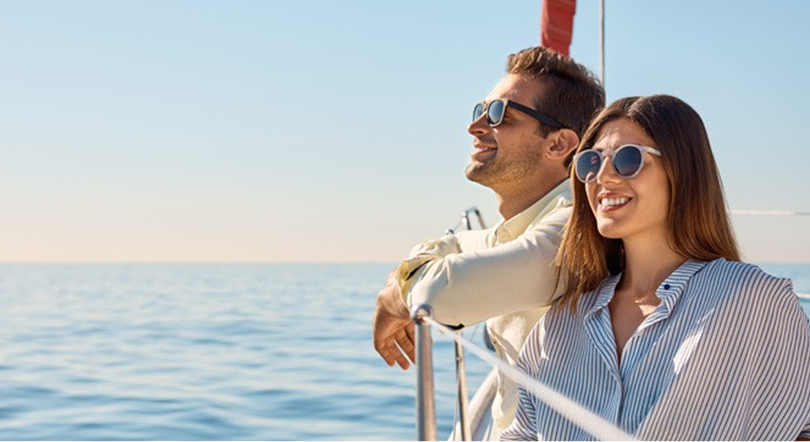 A smiling ad relaxed couple leaning on the balcony of a cruise ship, overlooking the ocean sea