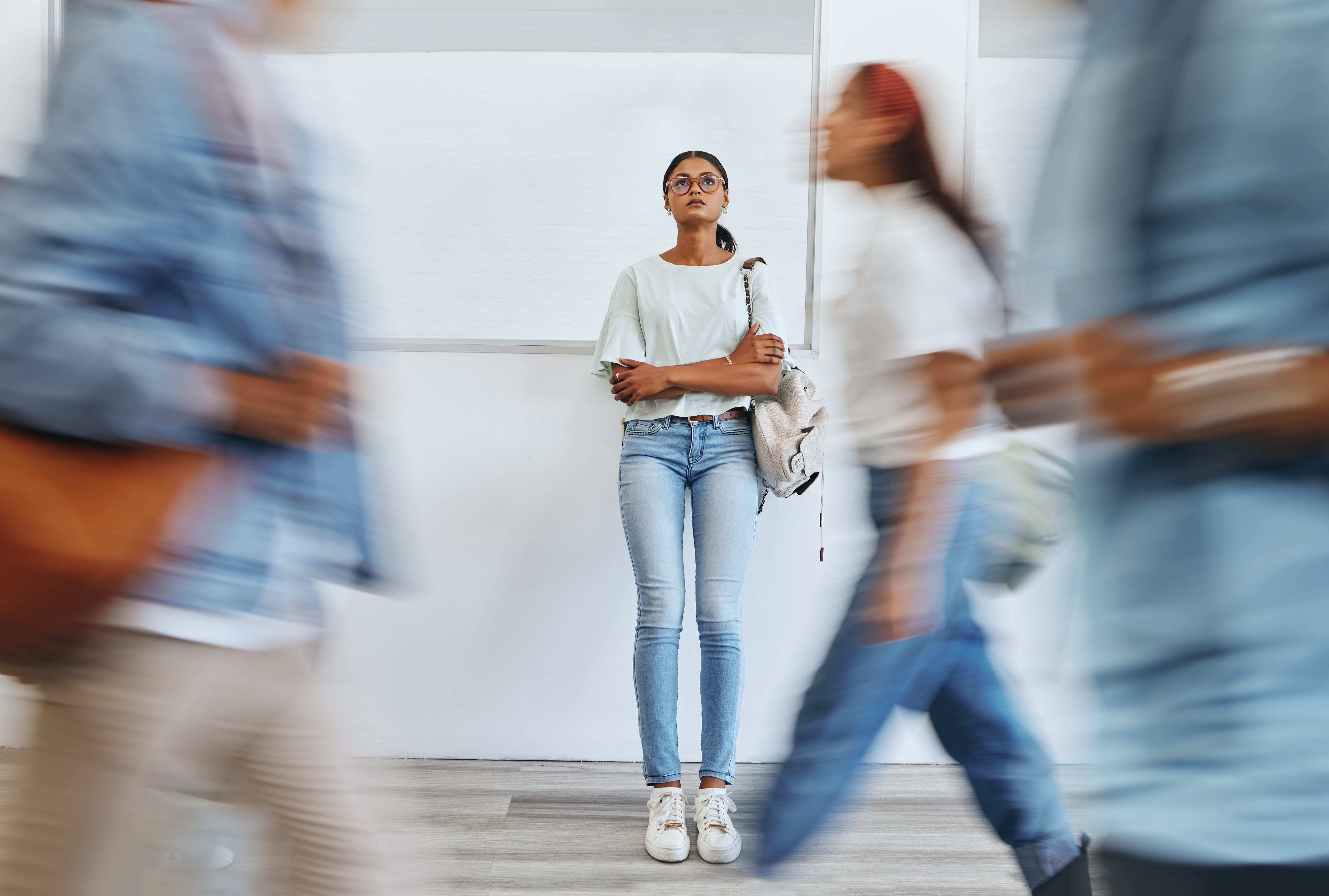 Person leaning against the wall with arms crossed as people walk past.