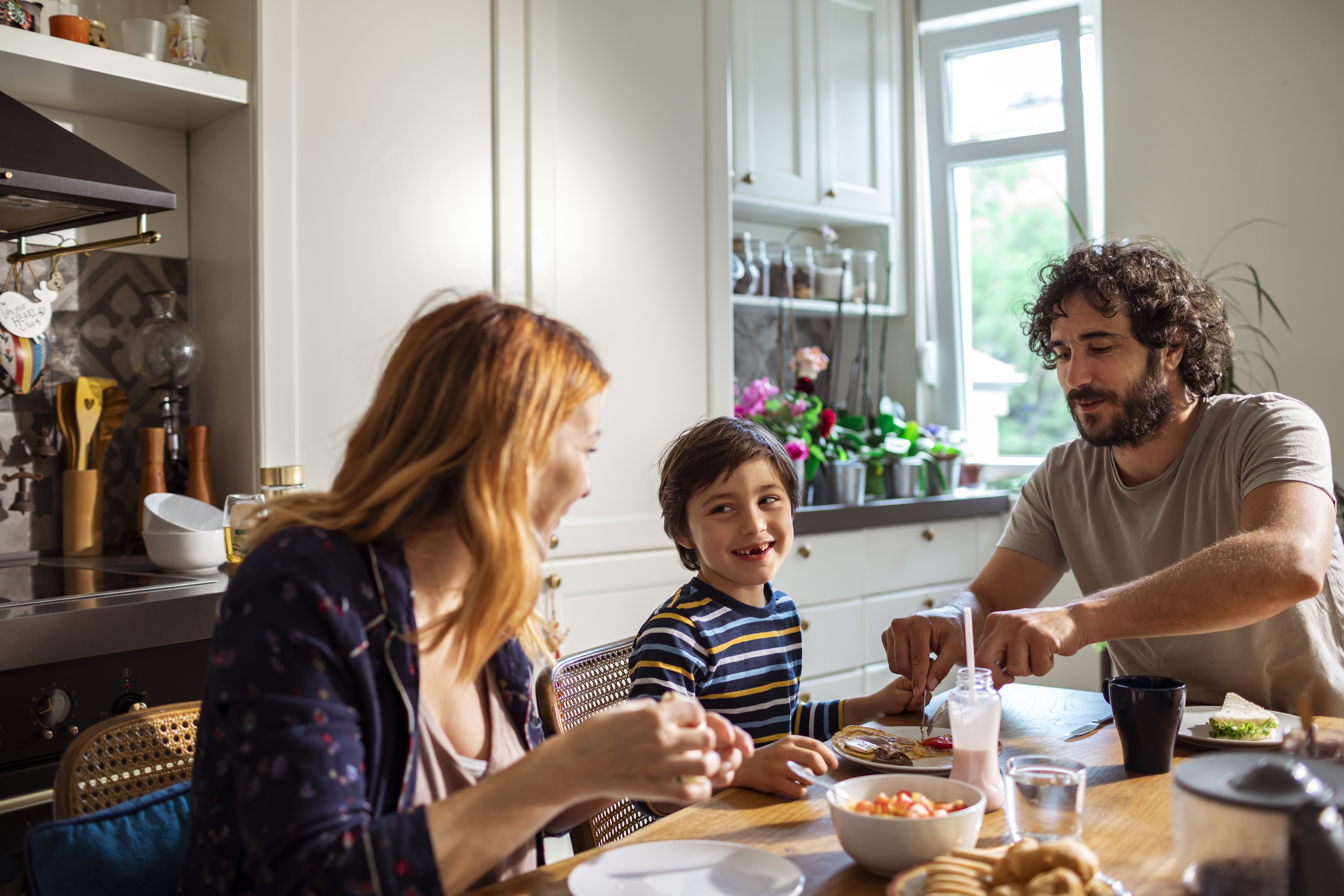 A mother, father and son sitting around the kitchen table eating breakfast