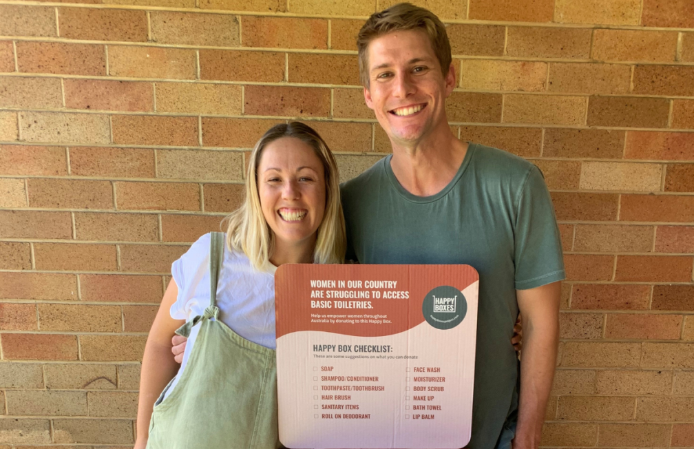 Two adults posing next to a Happy Box collection bin