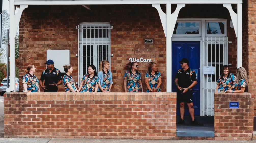 A group of people outside a WeCare building