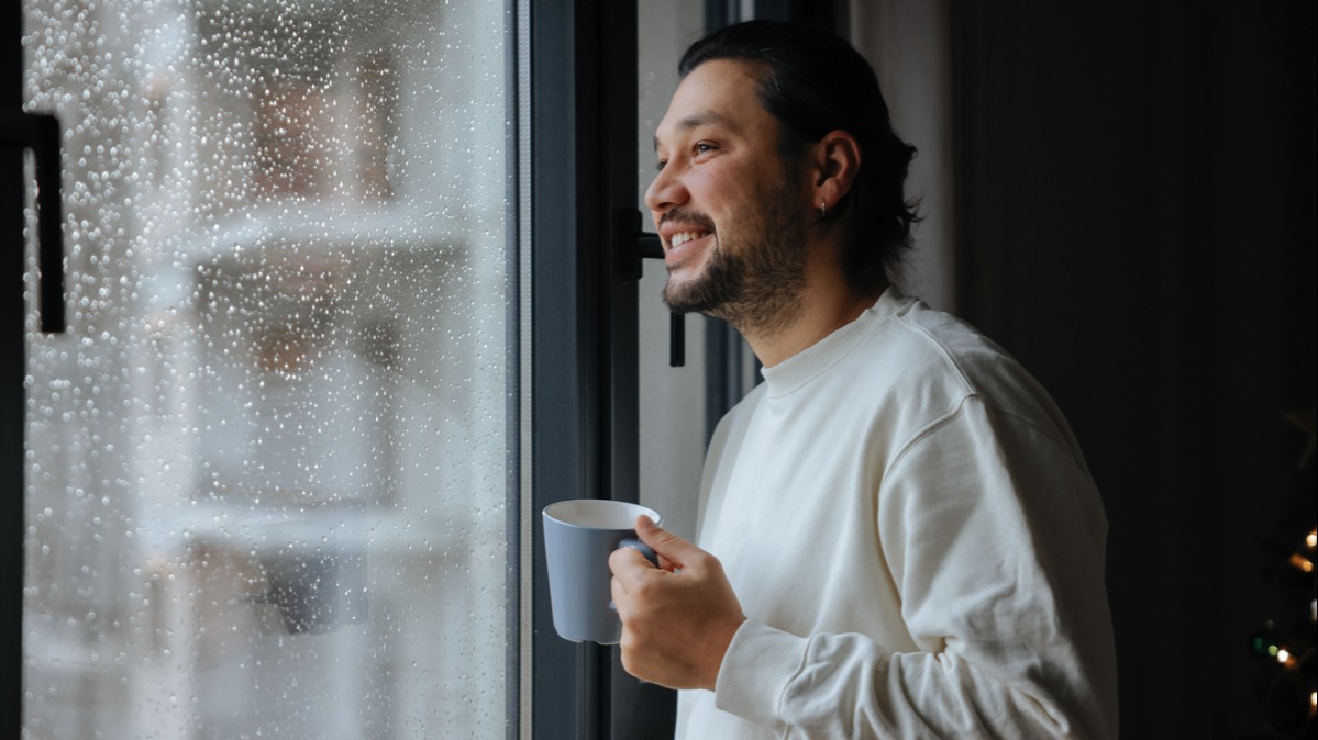 Person holding a mug and staring out the window.