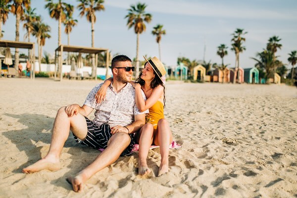 A couple sitting on the beach, embracing and smiling