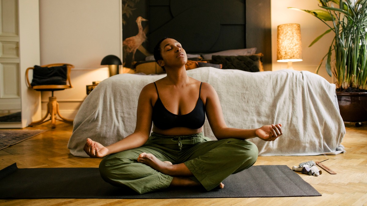 Person meditating on exercise mat in their bedroom.