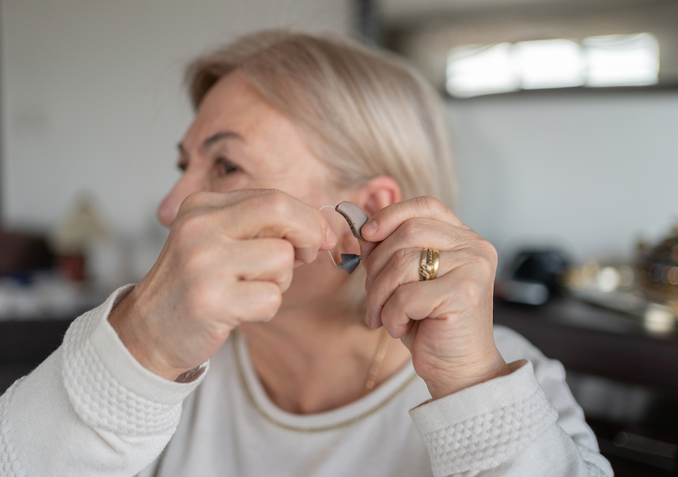 Old Woman Holding A Hearing Aid