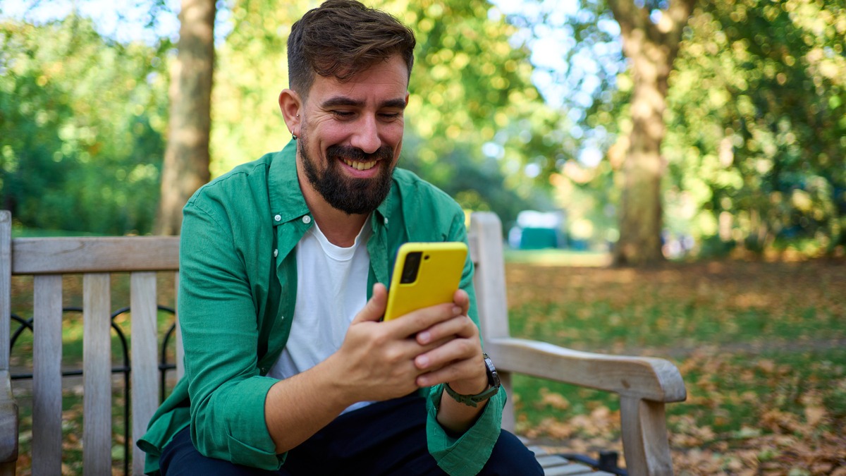 Person sitting on a park bench, looking at their phone.