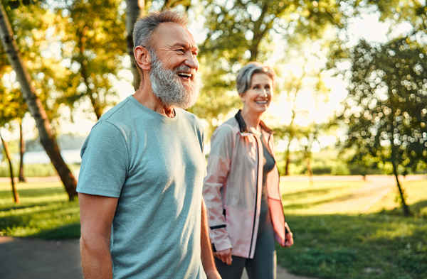 An older man and woman going for a walk in a leafy green park