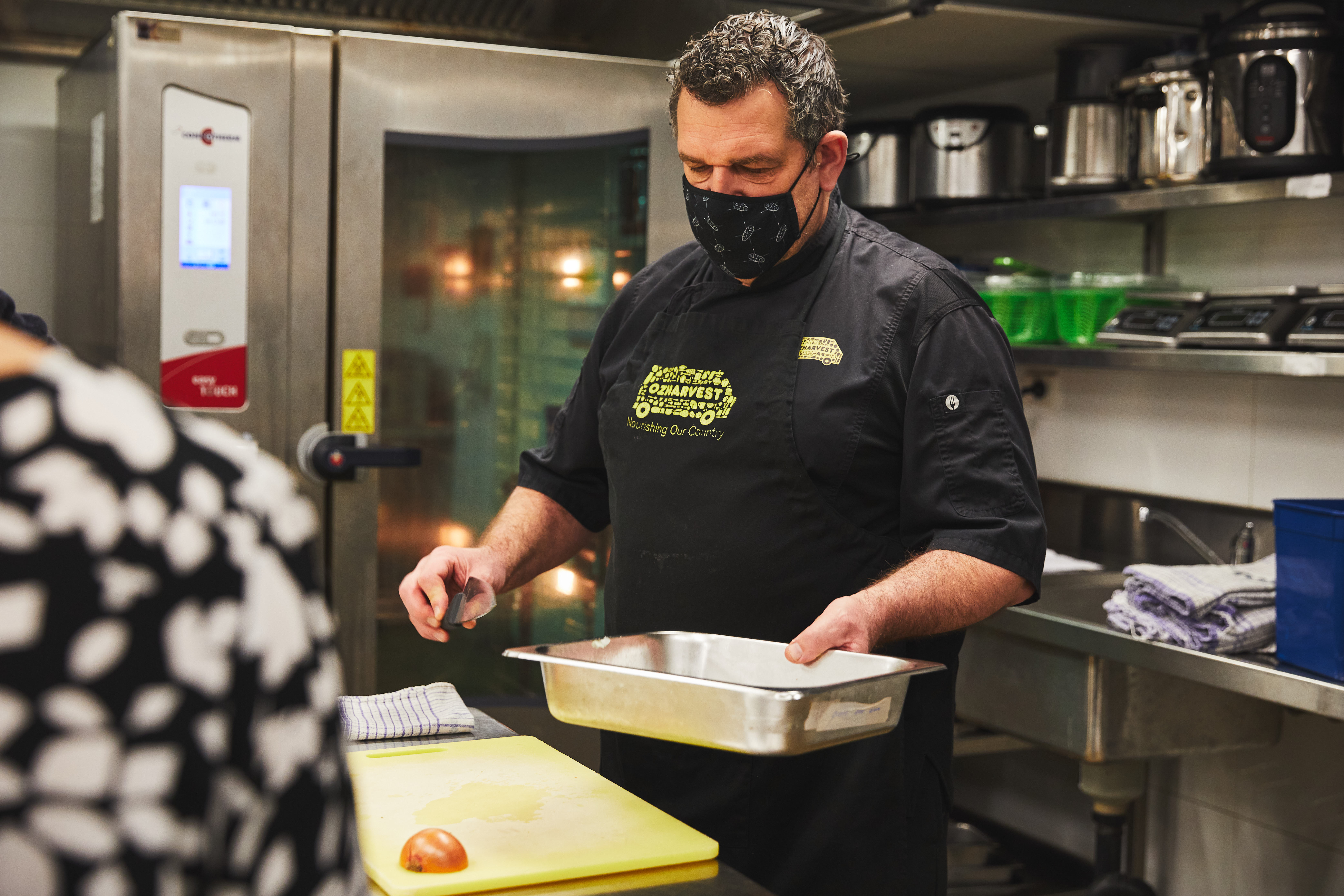 OzHarvest chef in the kitchen holding a cooking tray