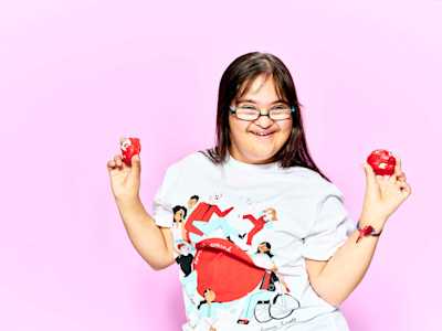 Young person smiling and holding two red noses