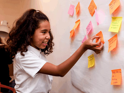 A child sticking a post it not to a piece of paper