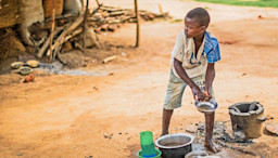 A young boy in poverty, getting some water.