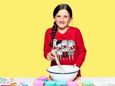 Child stirring a mixing bowl with a wisk.