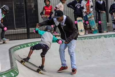 A man helps a child skateboard