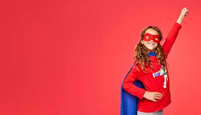 A girl wearing a superhero outfit, her arm raised like she's flying.