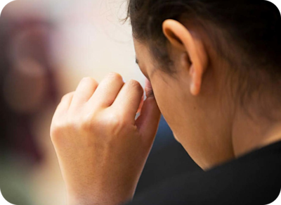 a person with their head down, wiping a tear