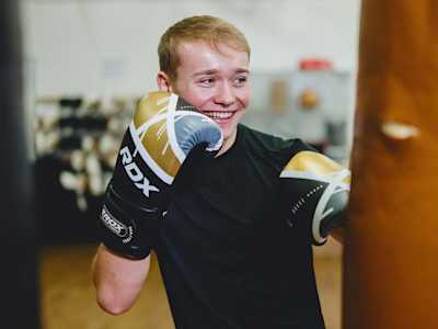 Billy smiling as he punches a punching bag.
