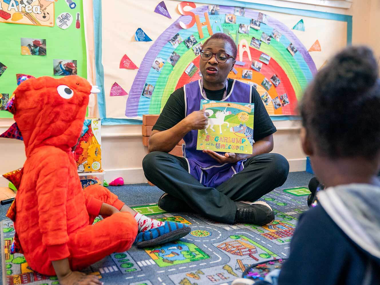 Miriam reading a picture book to children.
