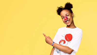 A girl smiling and wearing a red nose and a TK Maxx t shirt.