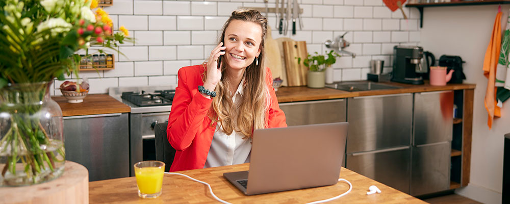 Bellende vrouw met laptop die naar een bos bloemen kijkt.