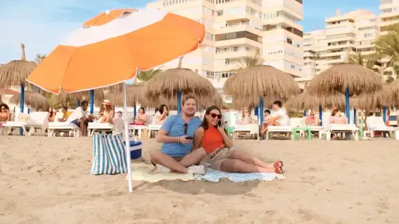 man en vrouw onder parsol op het strand