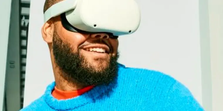Man met een blauwe truit aan en VR-bril op, lacht