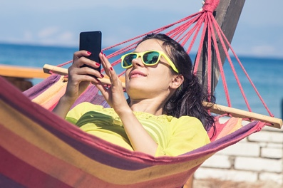 Vrouw in hangmat aan de zee met haar telefoon in de hand met 4G