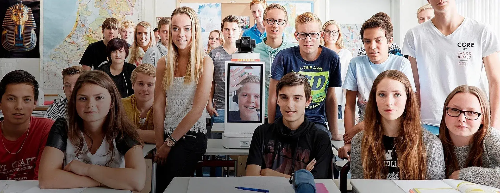 Schoolklas met in het midden de vernieuwde Klasgenoot waarmee het zieke kind thuis mee kan doen in de klas