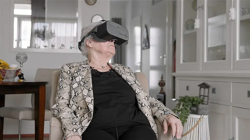Oudere dame zit in stoel met VR bril op