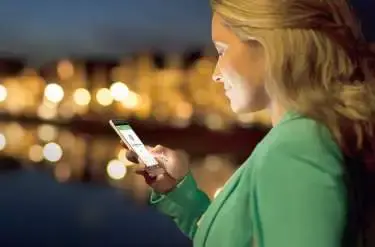 Dame kijkt bij ovandlicht op telefoon