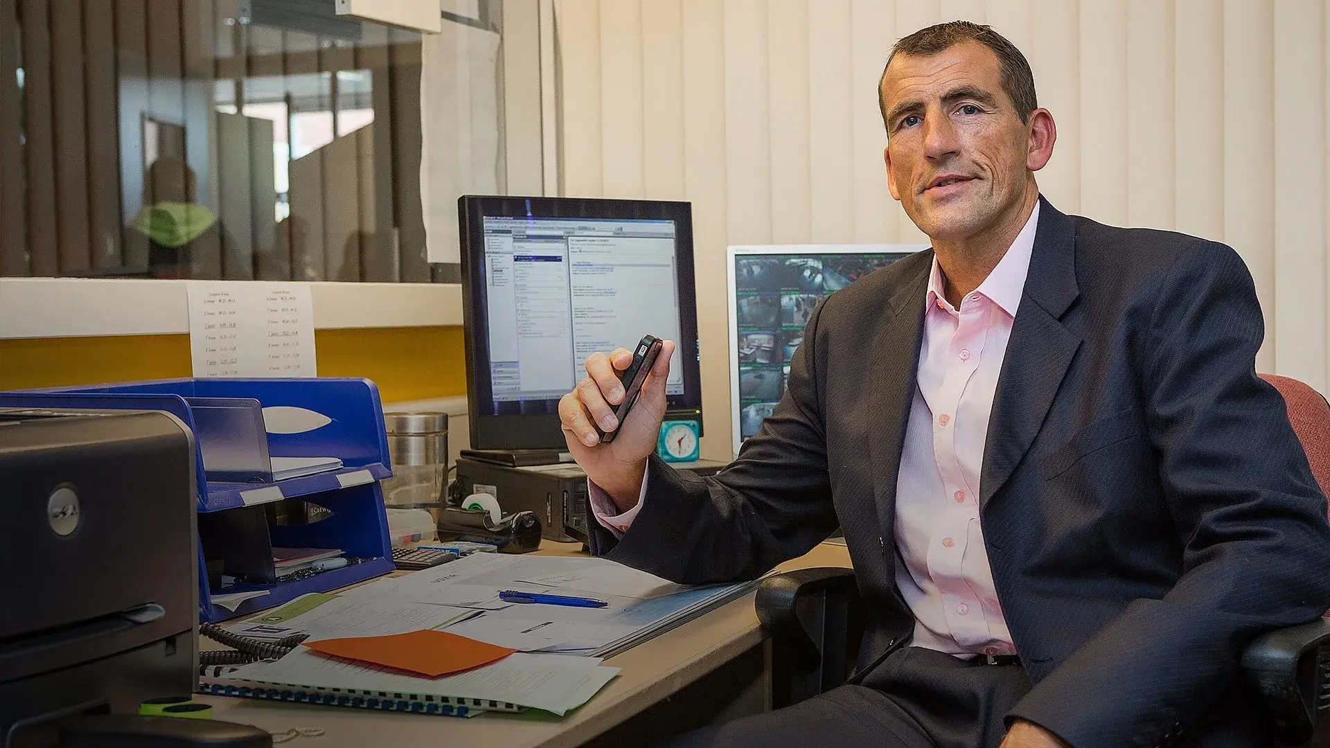 Man zit achter een bureau kijkt naar de camera