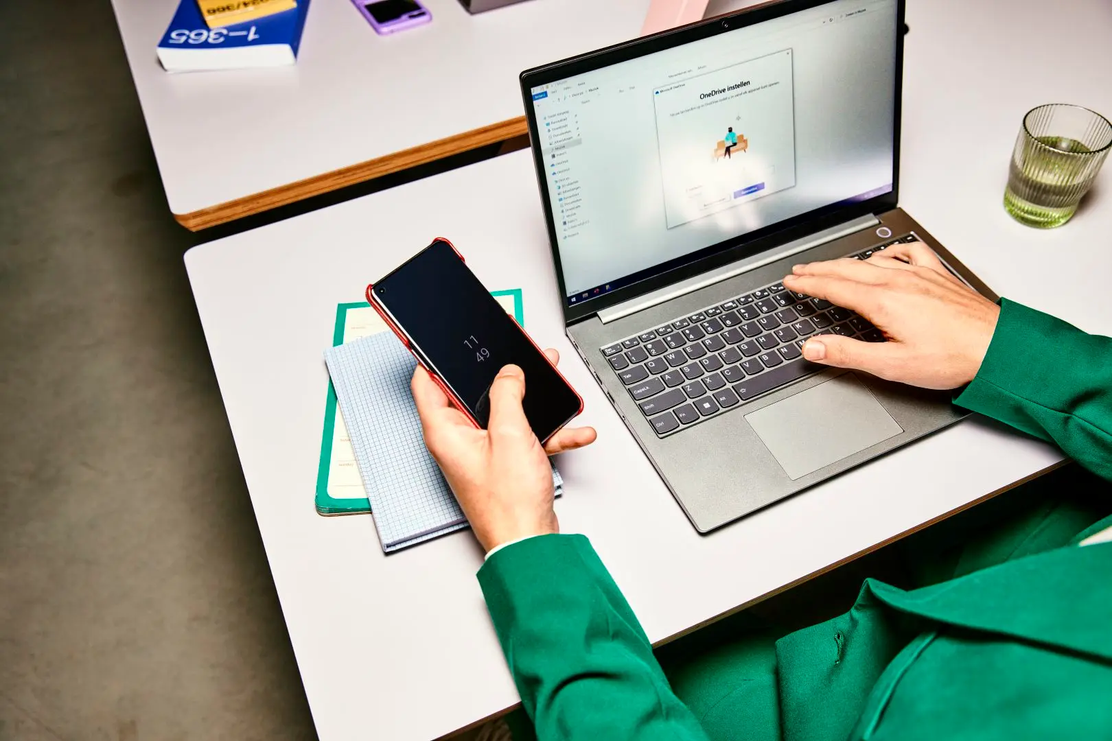Iemand werkt met een laptop en houdt een mobiele telefoon vast.