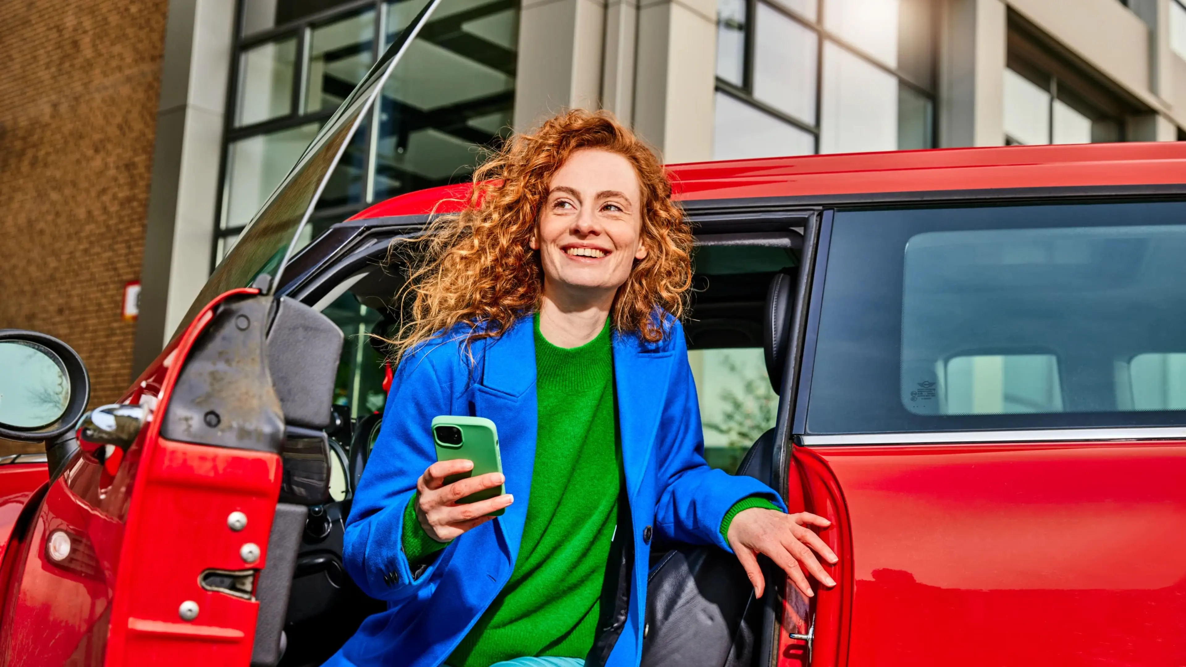 Vrouw met mobiel telefoon stapt uit rode auto