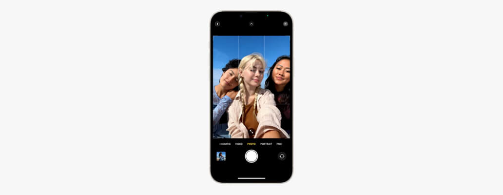 Een iPhone 14 =met de camera open. Er is een beeld te zien van drie meiden die een selfie maken