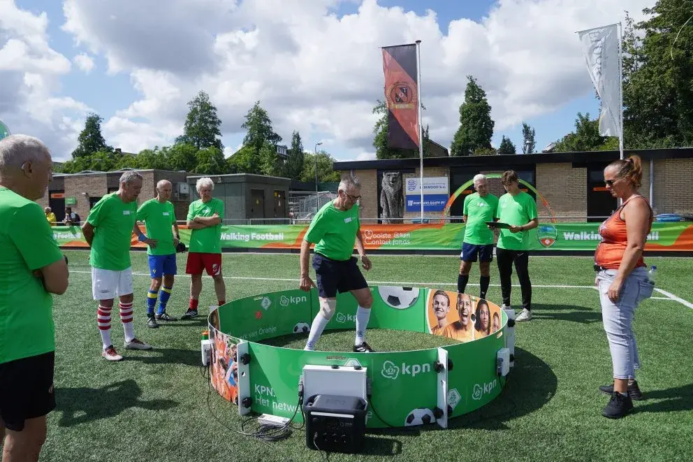 Spelers Walking Football kijken toe hoe een speler op de training met een bal bezig is