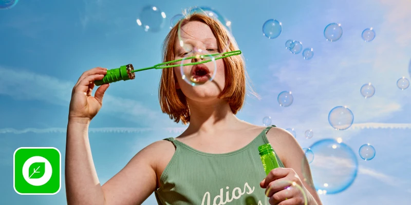 meisje blaast grote bubbels met bellenblaas in zonnig weer