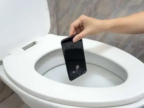 persoon houdt telefoon bij een geopende wc pot